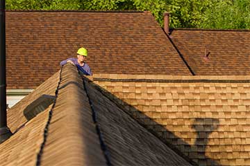 Roofing technician inspecting a shingle roof